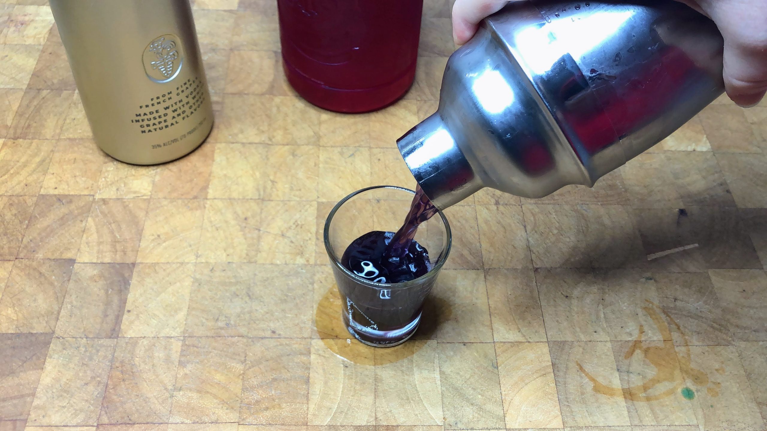Pouring purple gatorade shot from shaker into shot glass.
