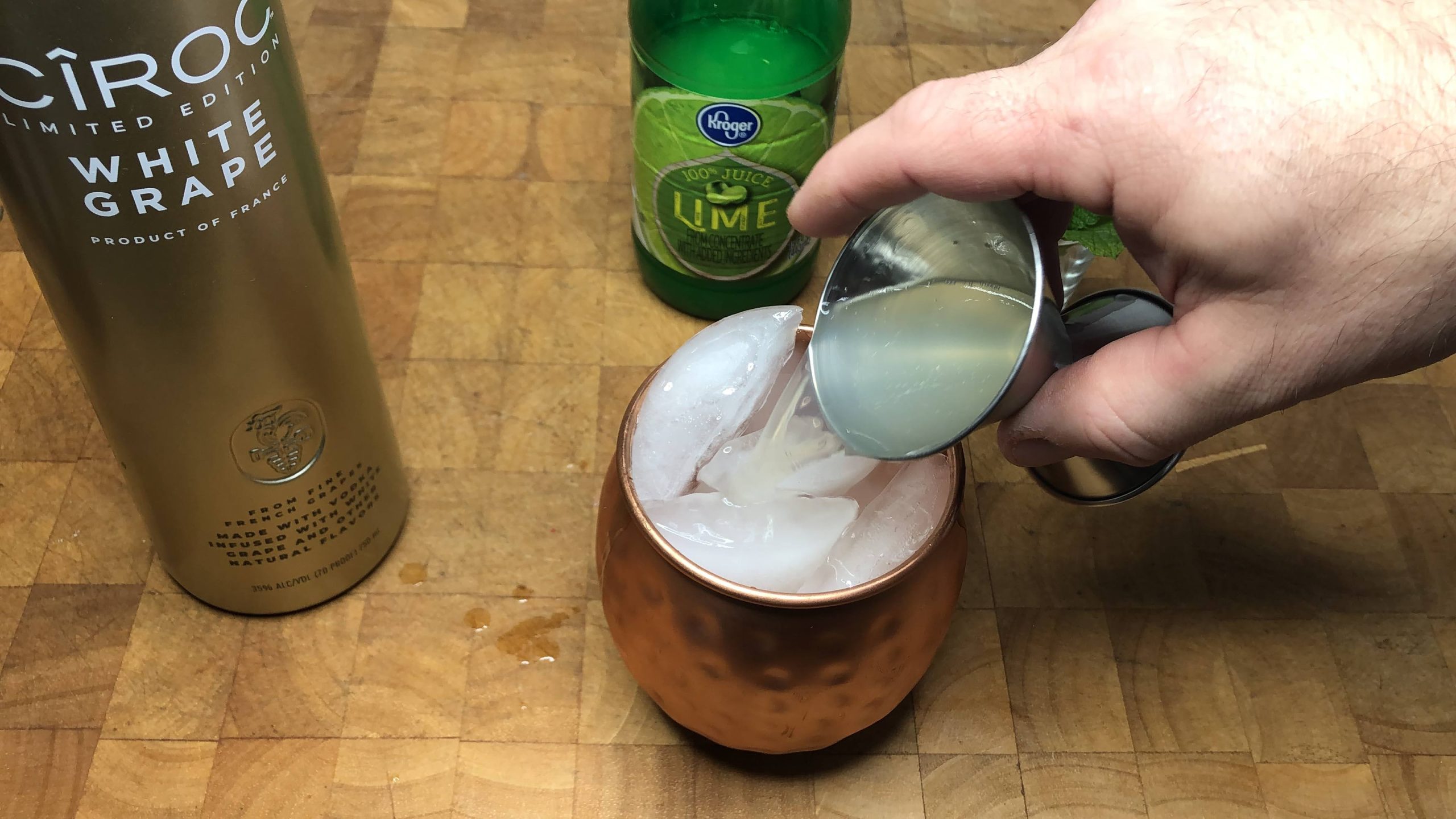 Pouring ginger beer from a jigger into a mug.