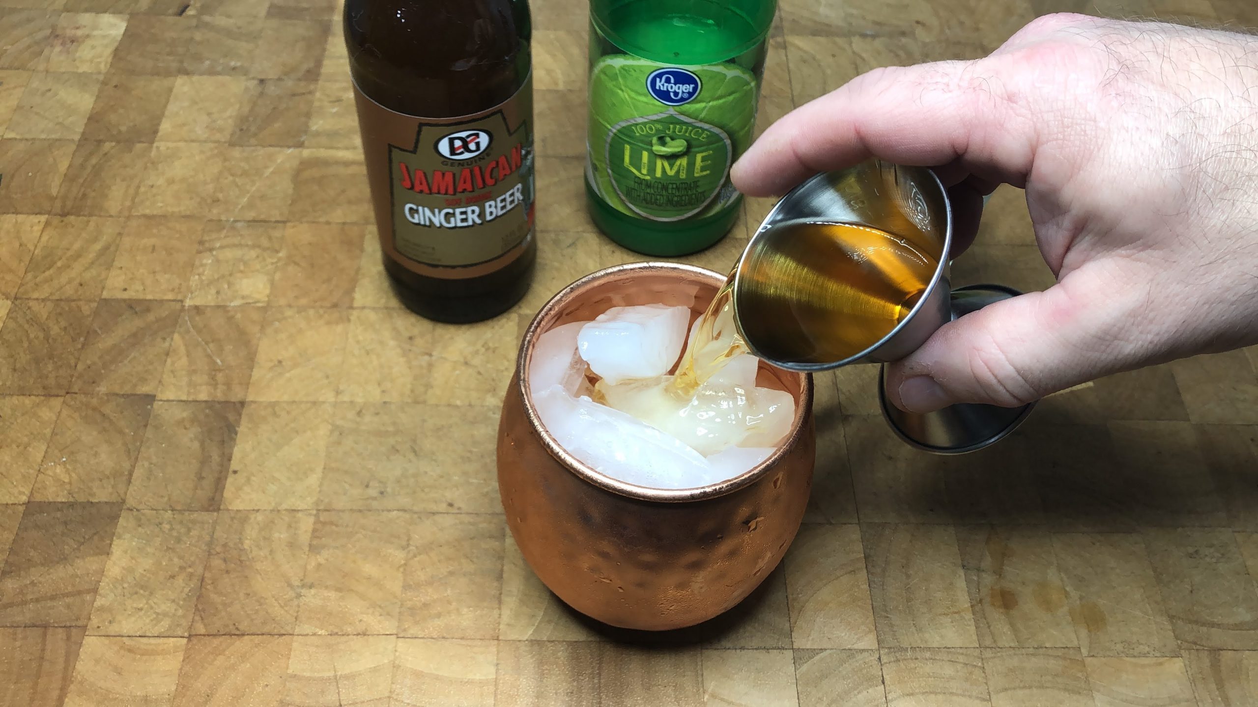 pouring jameson from jigger into copper mug