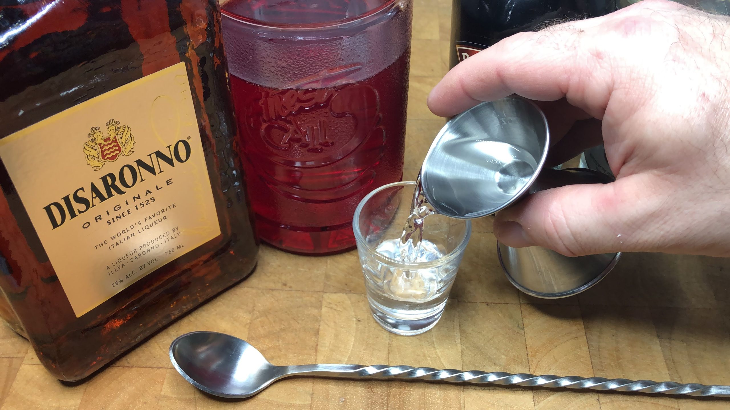 Pouring creme de cacao from jigger into shot glass.
