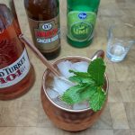 top down view of a kentucky mule with spring of mint in the mug and ingredients next to the drink.