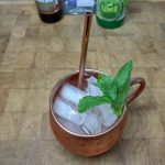top down view of a mexican mule in a copper mug with a sprig of mint and ingredients in the background