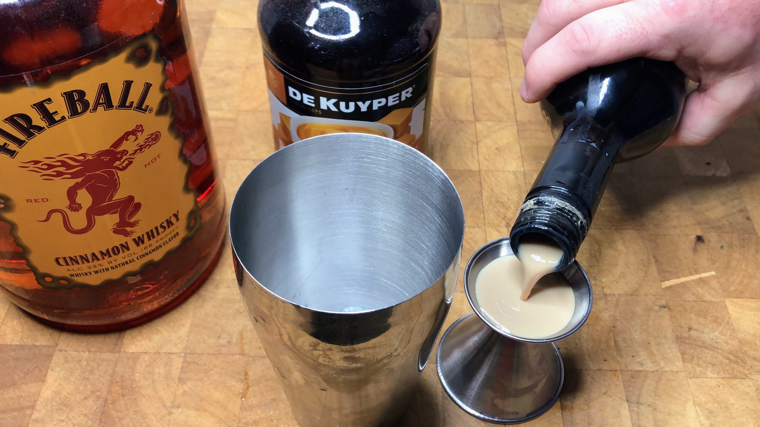 Measuring irish cream in a jigger.