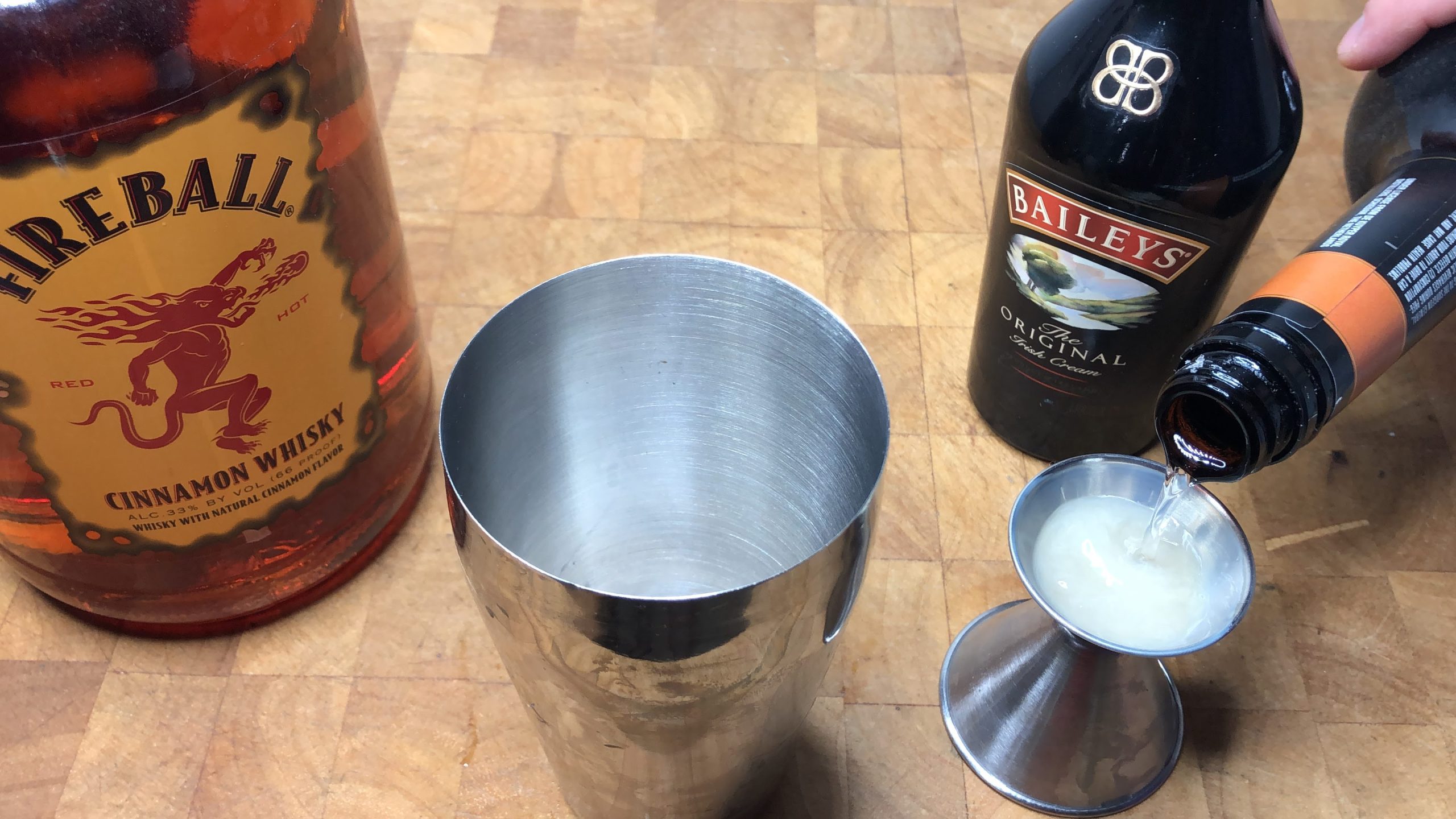 Measuring butterscotch schnapps with a jigger.