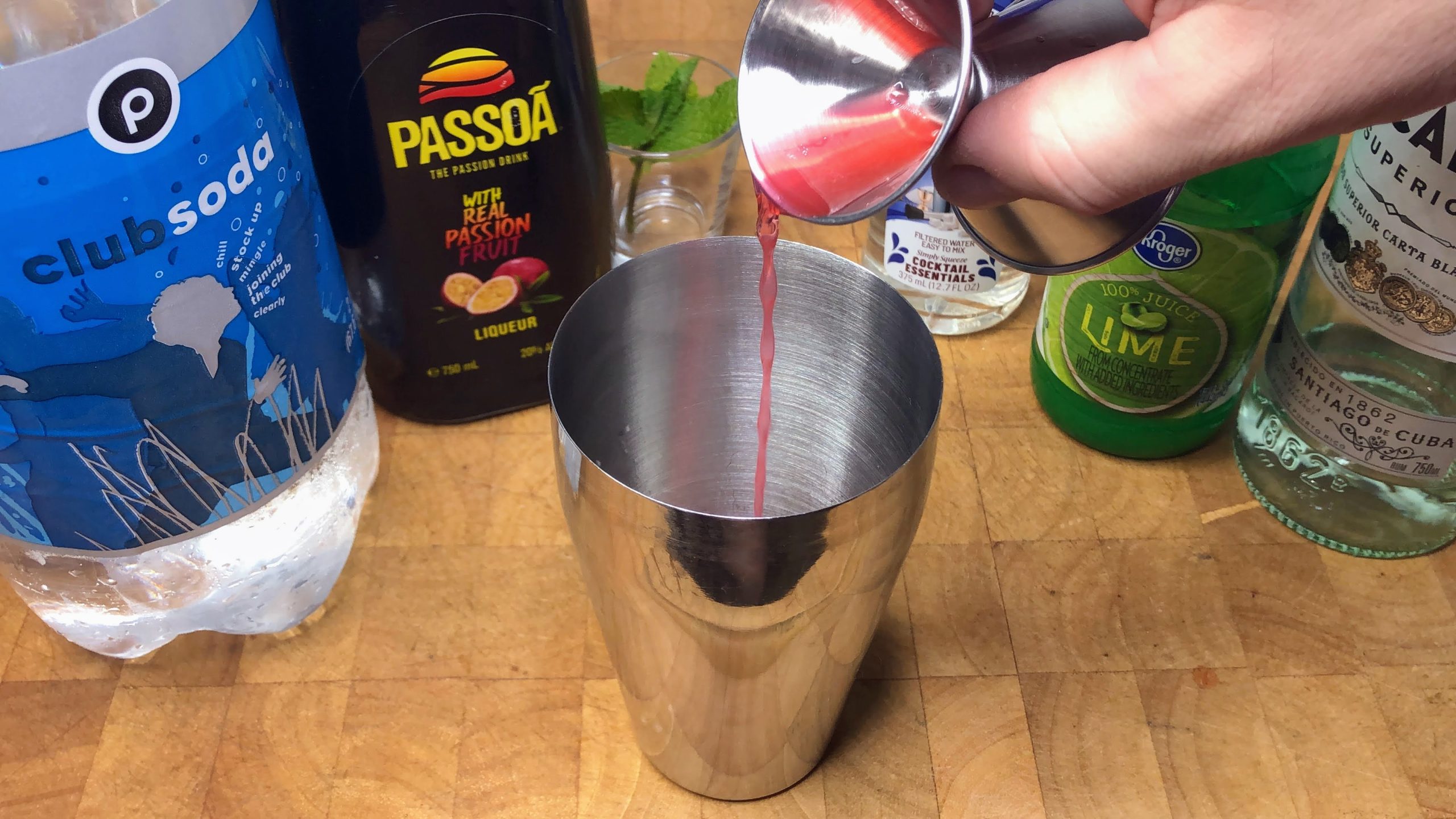 Pouring passoa from a jigger into a shaker.
