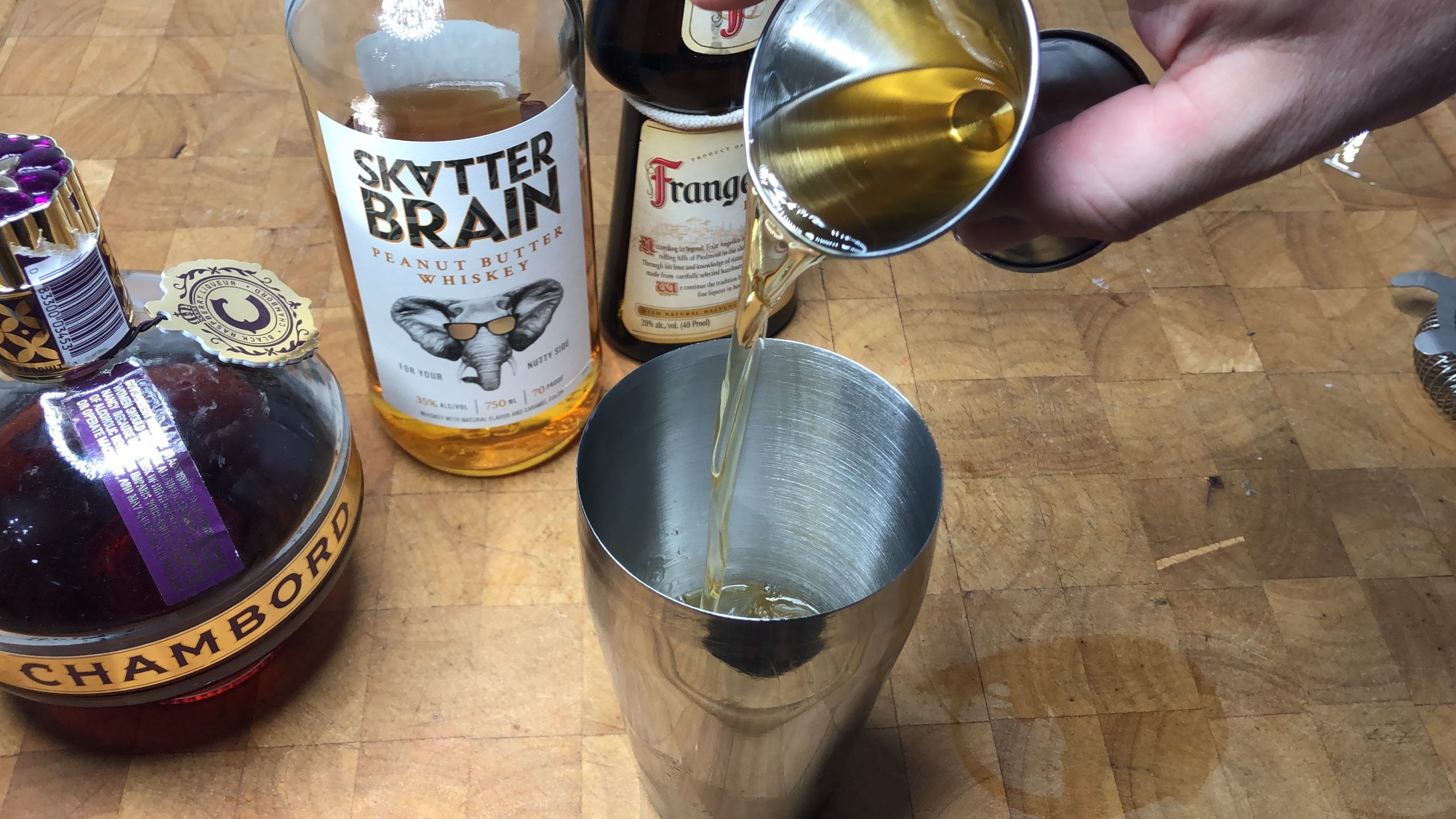 Pouring peanut butter whiskey from jigger into shaker.