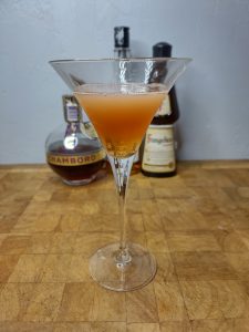 Peanut butter and jelly martini on a wooden table with ingredients in the background.