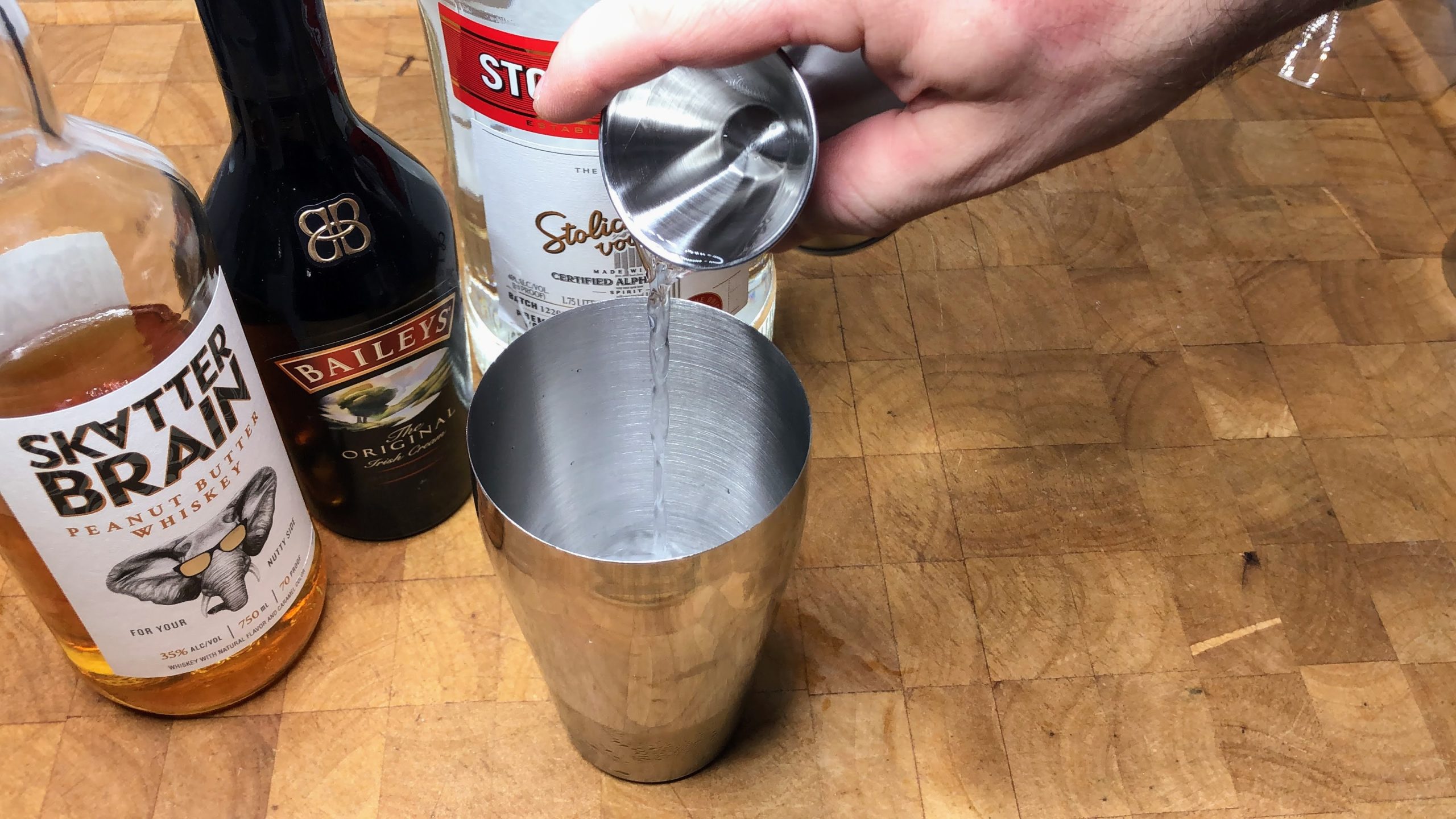 Pouring vodka from a jigger into a shaker.
