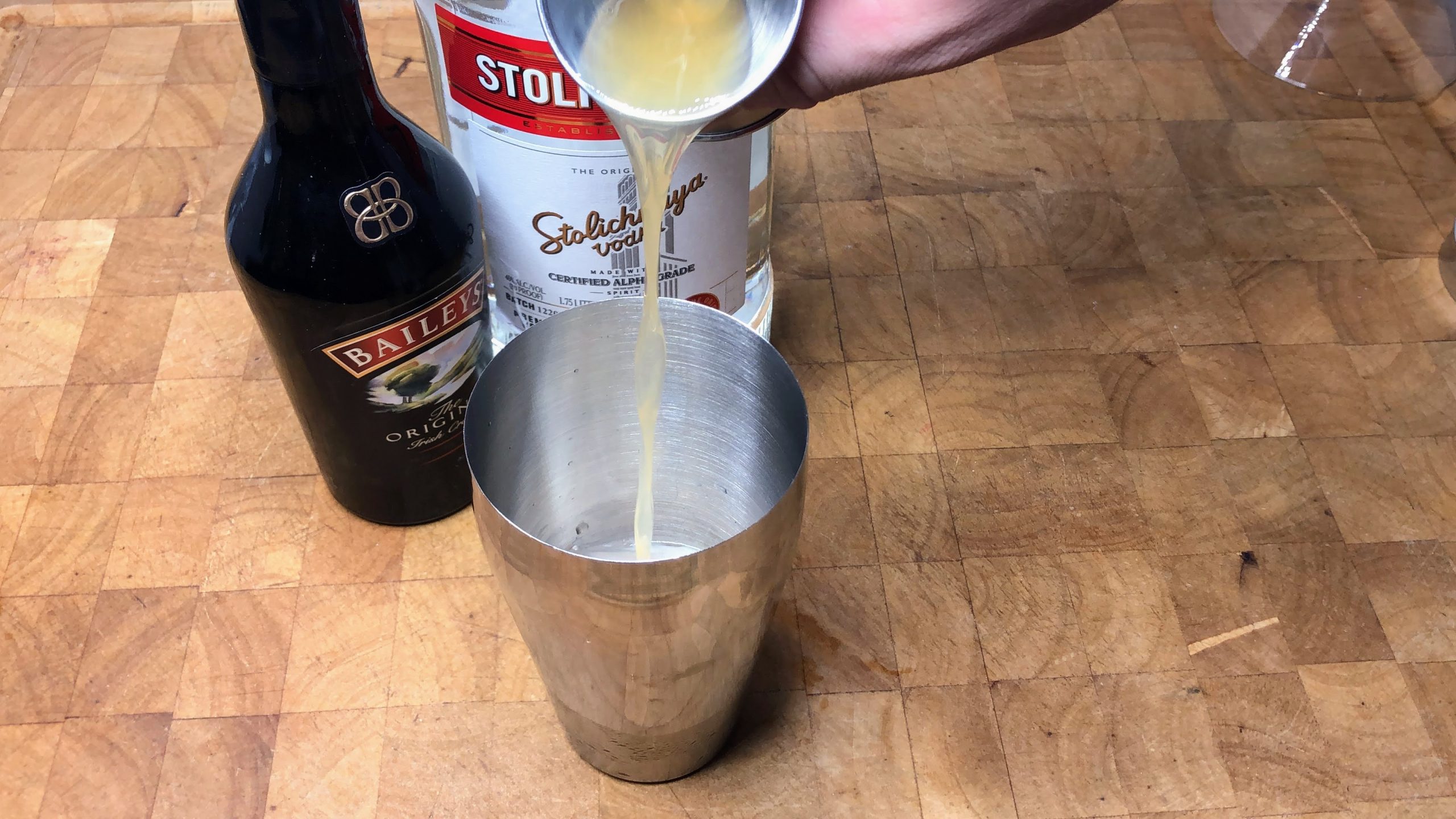 Pouring peanut butter whiskey from a jigger into shaker.