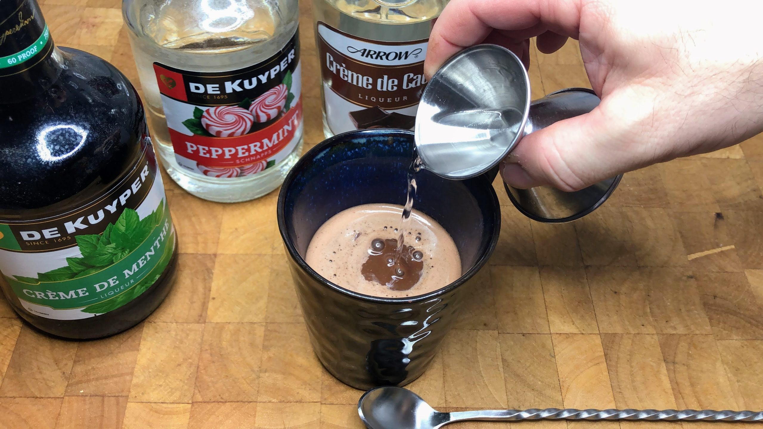 Adding creme de cacao into a mug.
