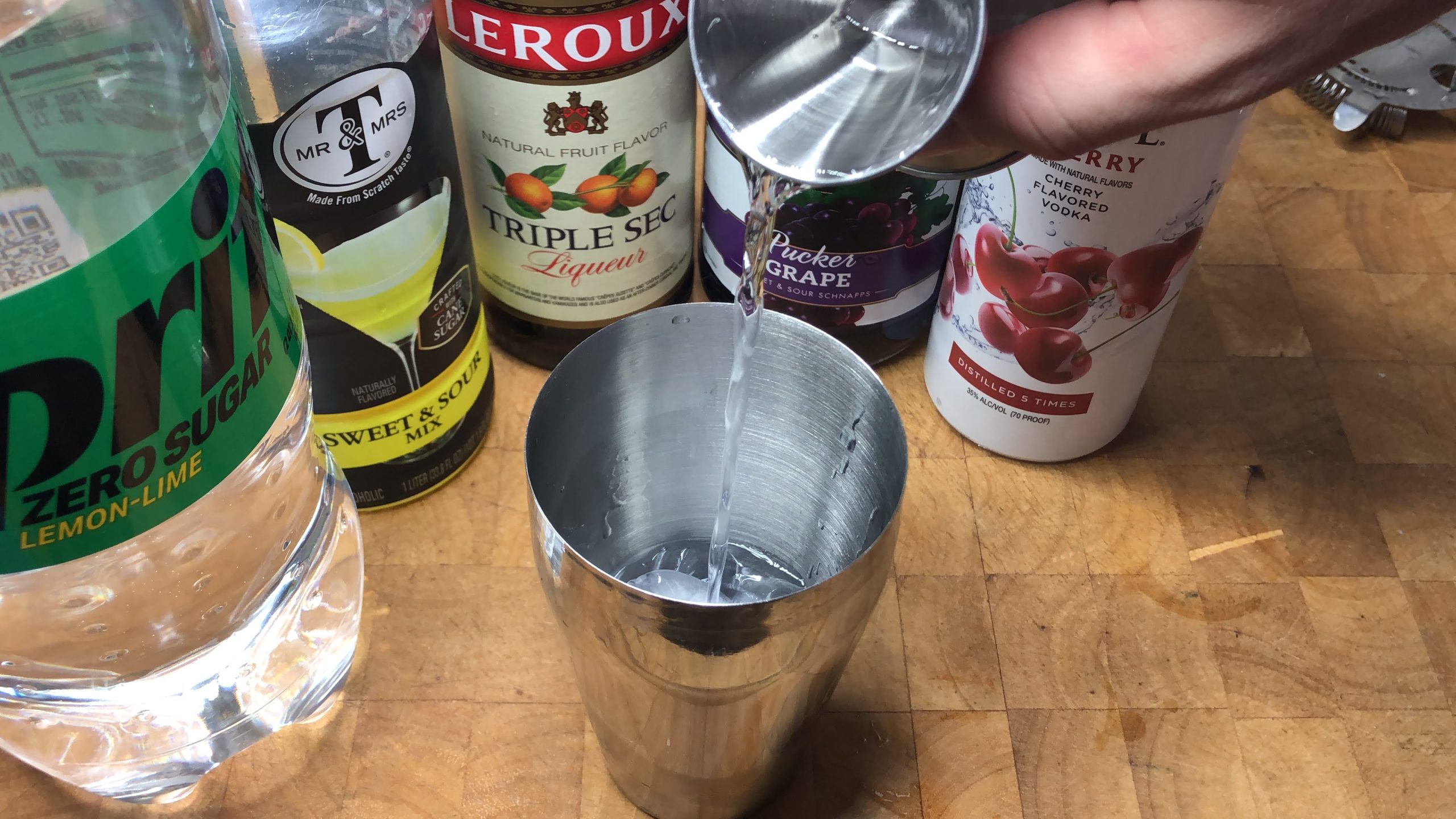 Pouring triple sec from a jigger into a shaker.