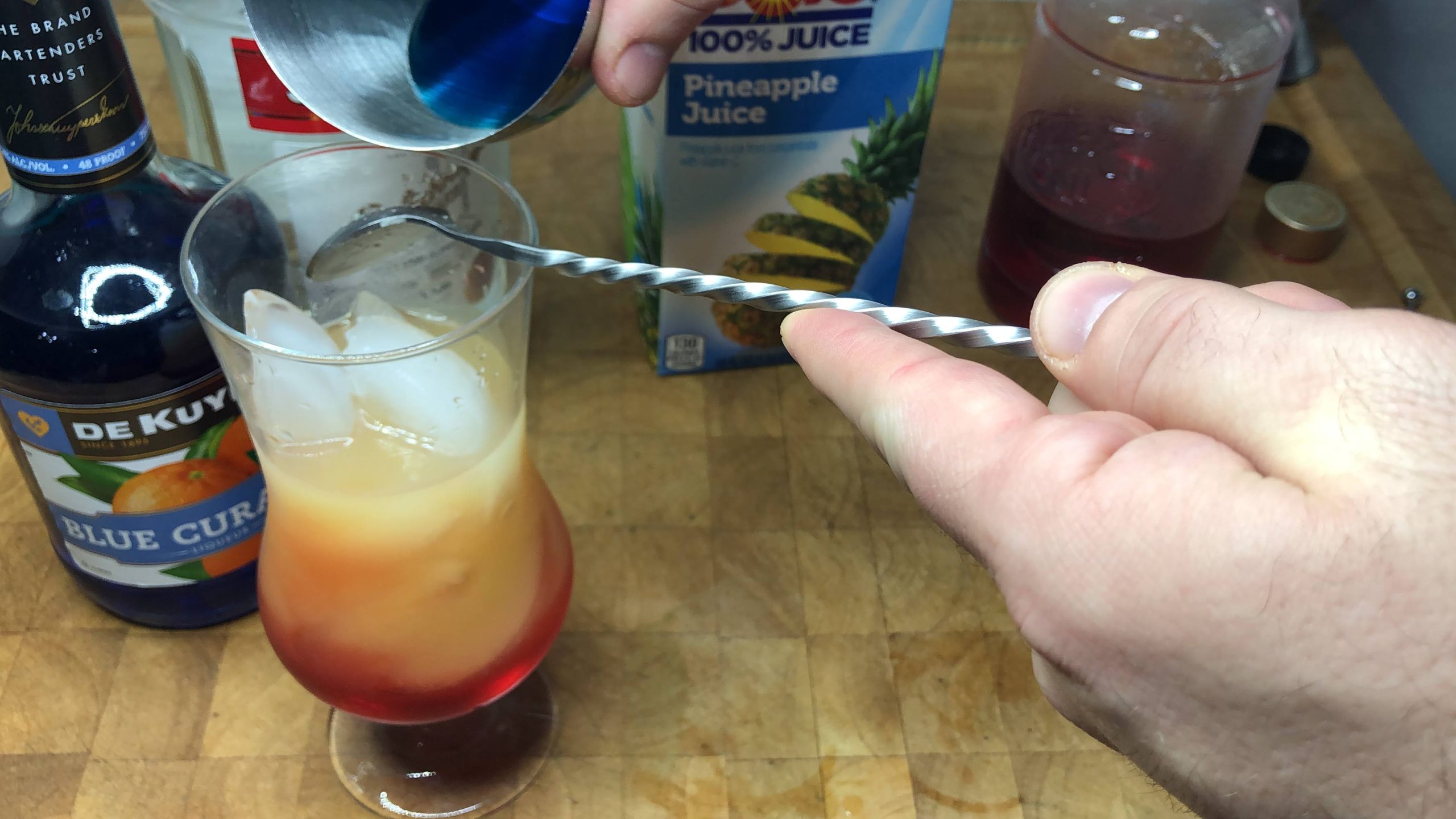 Layering blue curacao and vodka over a bar spoon.