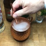 Adding a copper straw to a raspberry moscow mule.