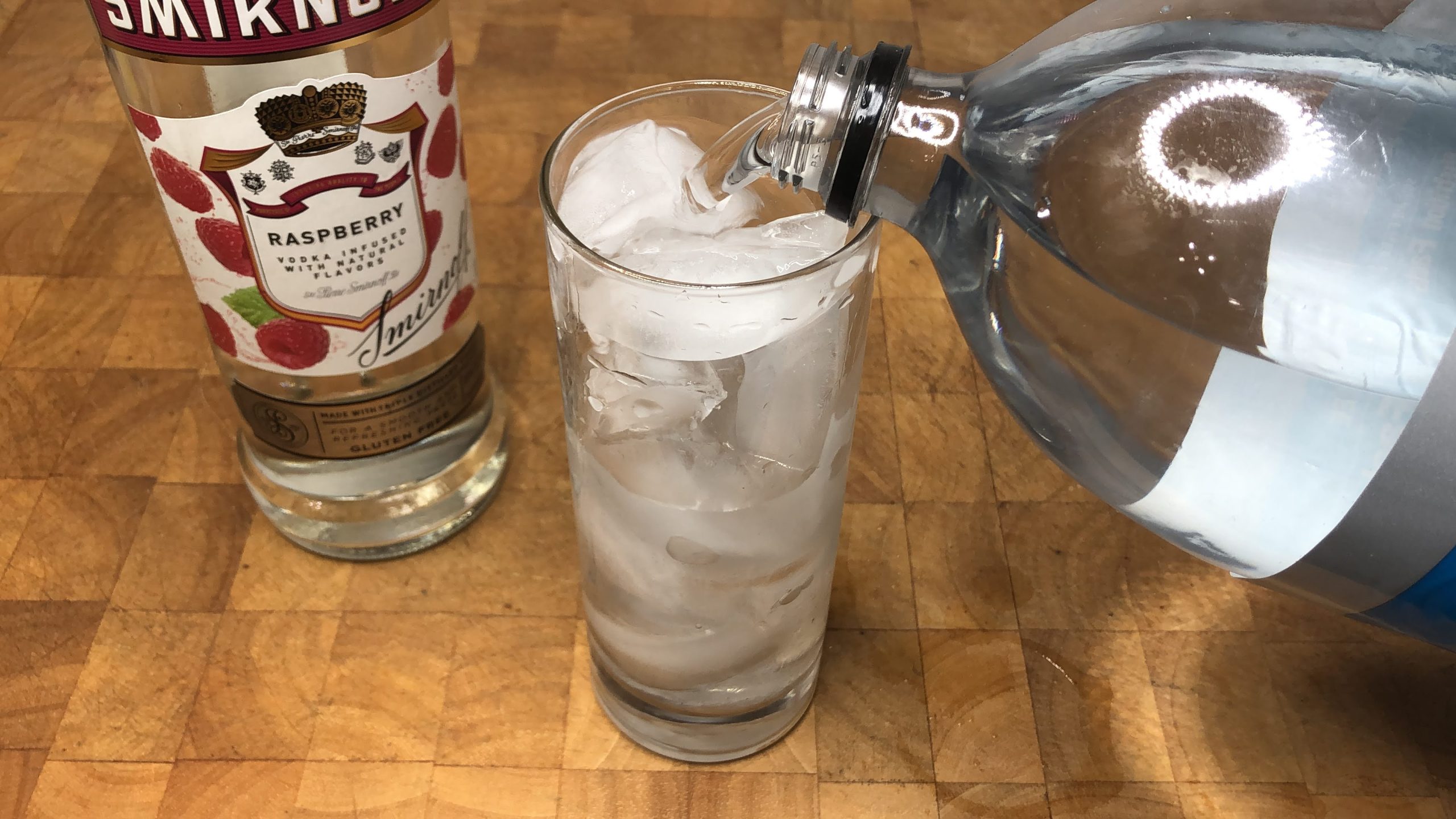 Pouring club soda into a highball glass.