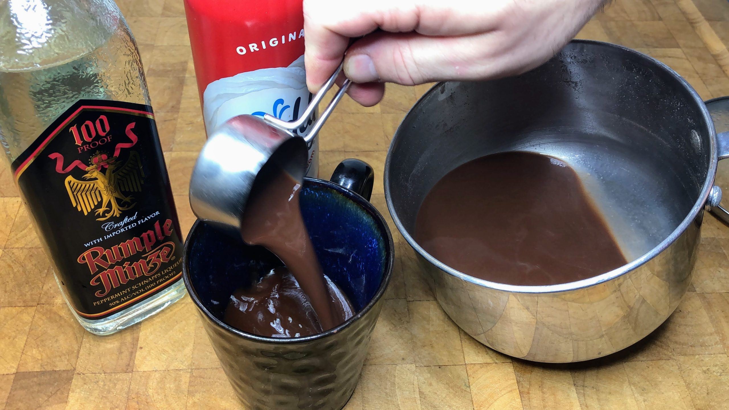 Pouring hot chocolate from measuring cup into mug.