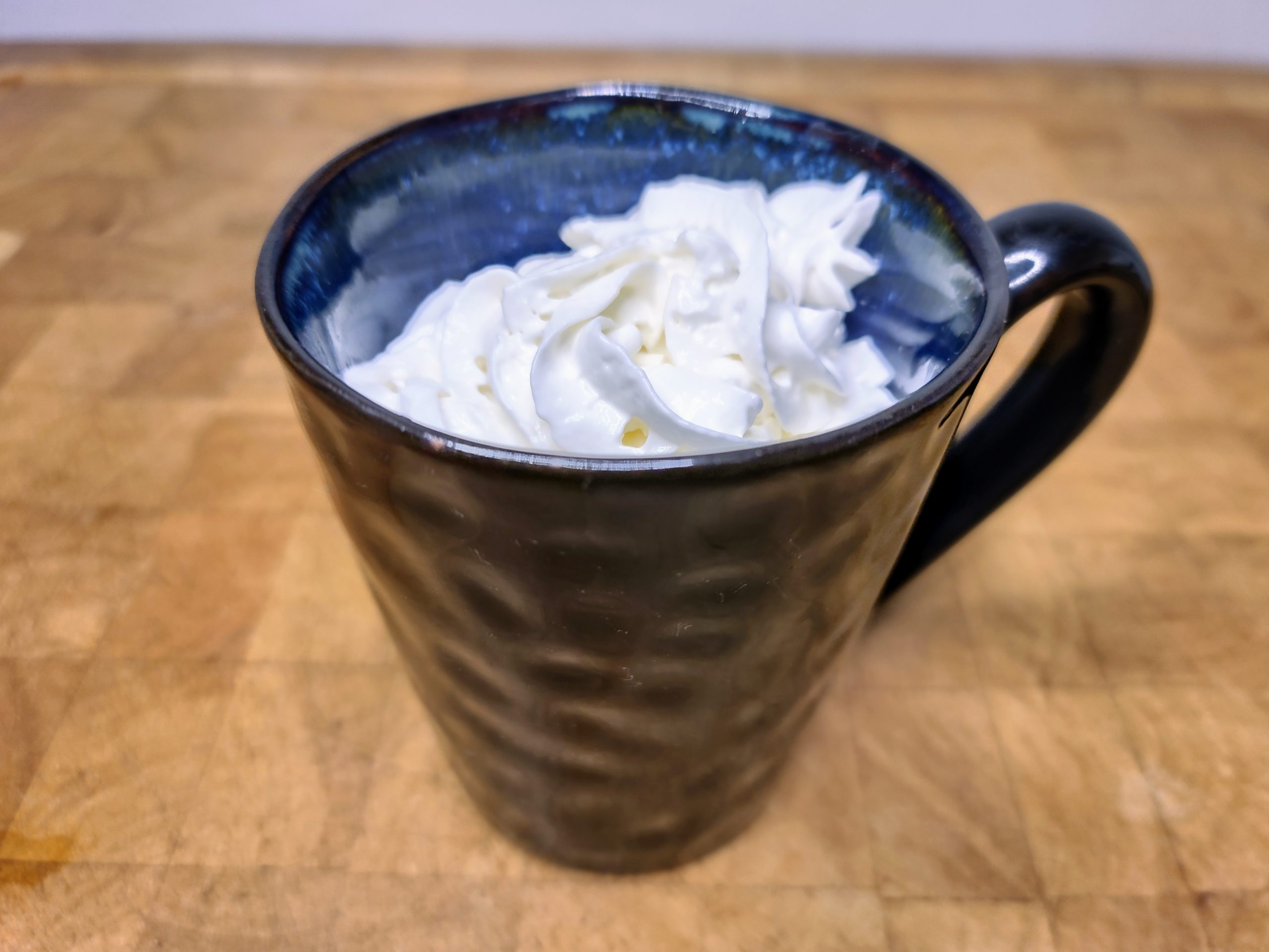 Rumplemintz hot chocolate in a blue mug topped with whipped cream.