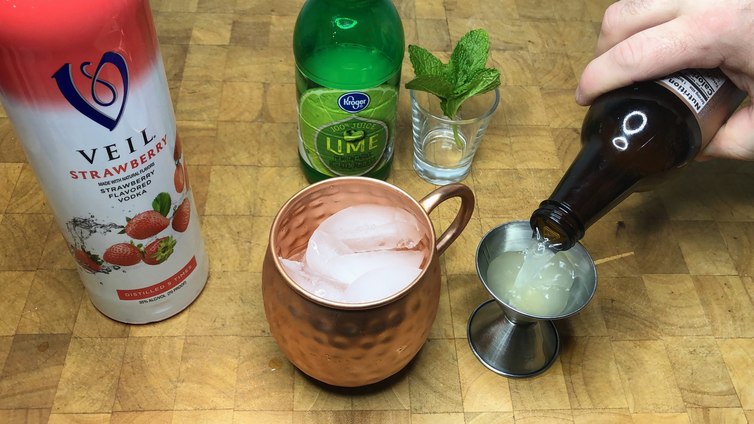 Pouring ginger beer into a jigger.