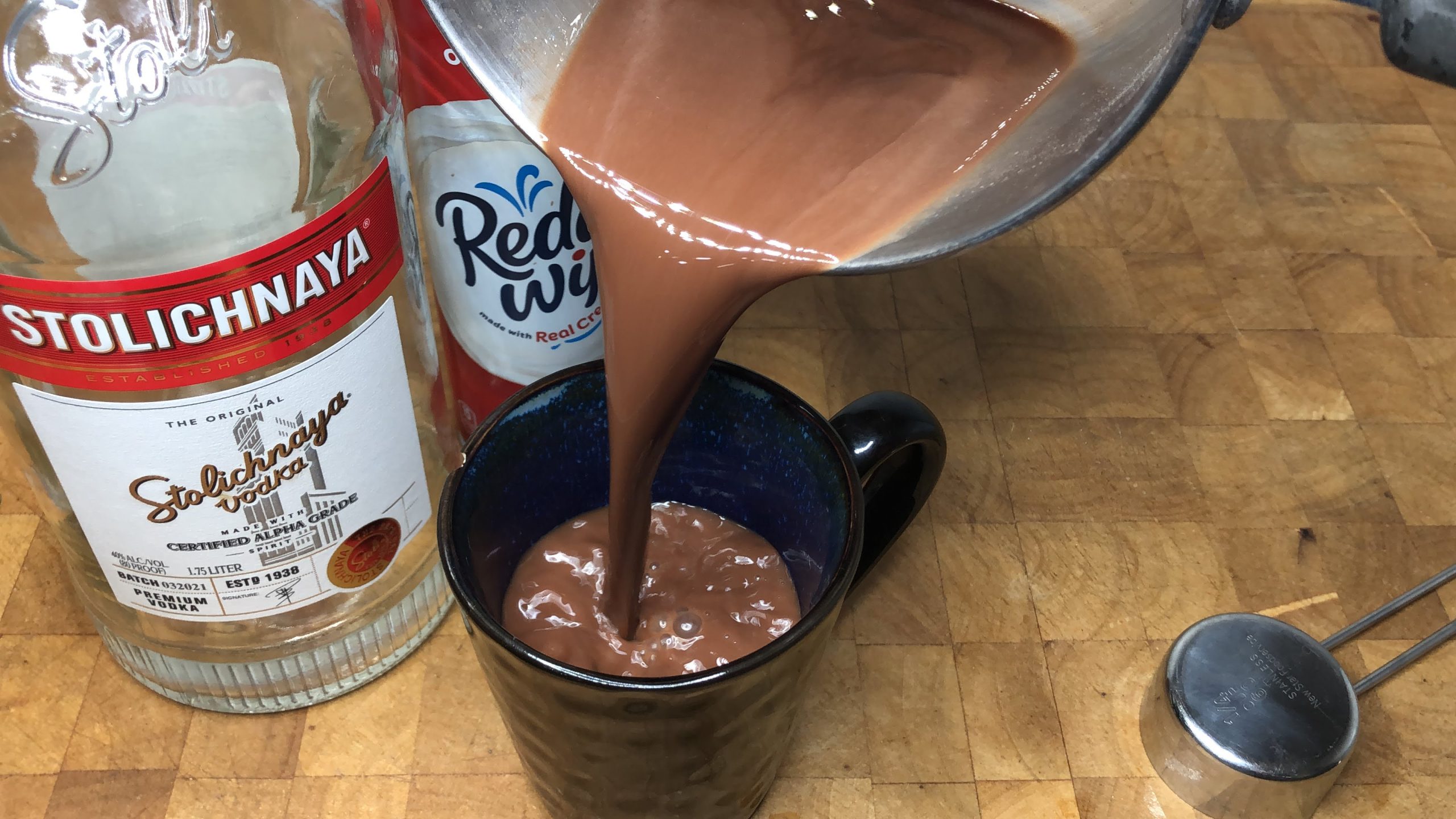 Pouring hot chocolate from pot into mug.