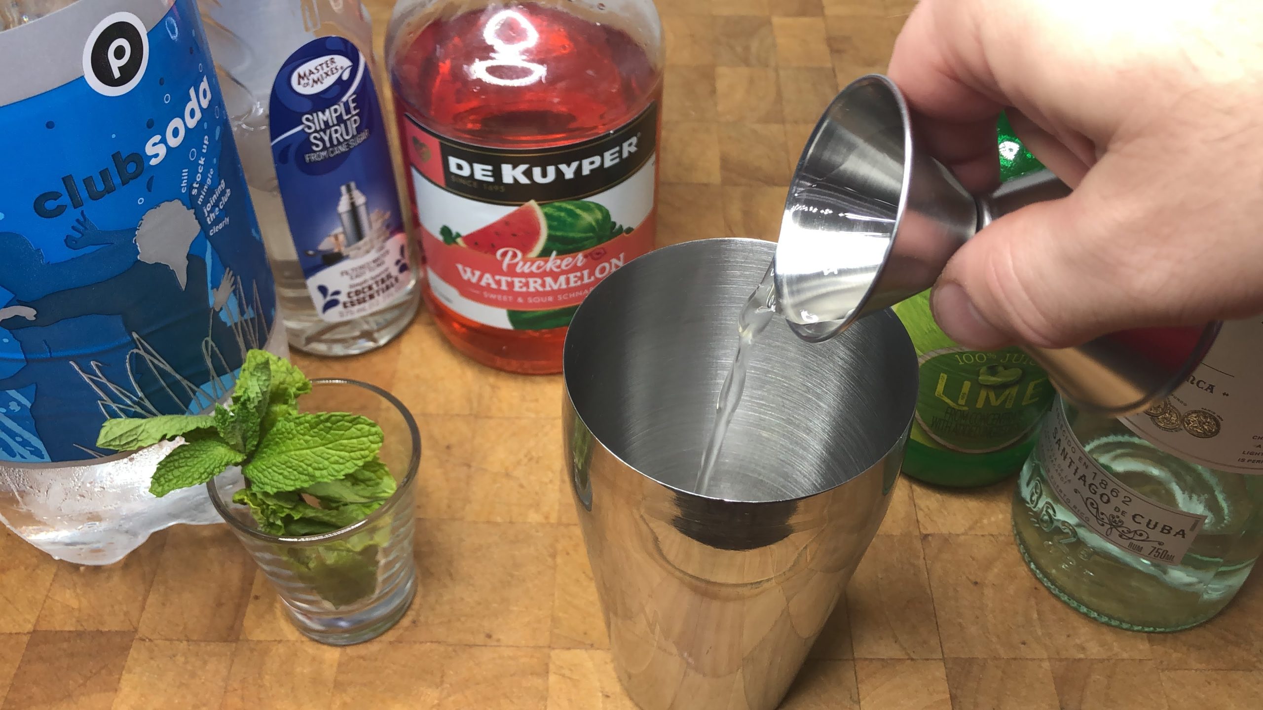Pouring simple syrup from a jigger into a shaker.
