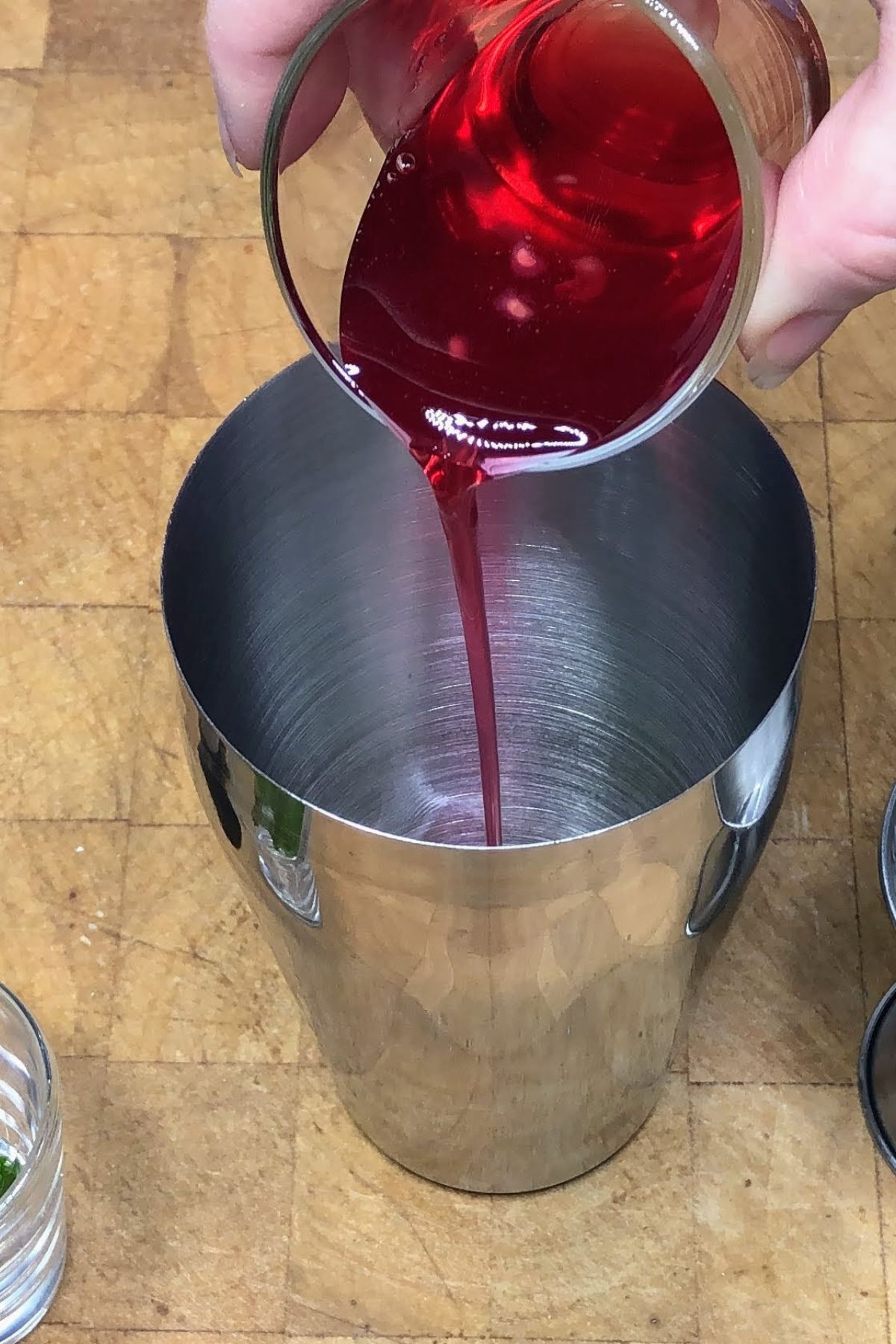 Pouring strawberry simple syrup into a shaker.
