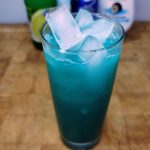 Blue Hawaiian Mocktail on a wooden table with ingredients in the background.