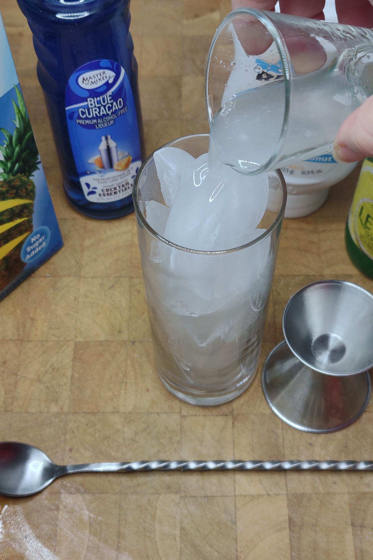 Pouring coconut simple syrup into a glass.