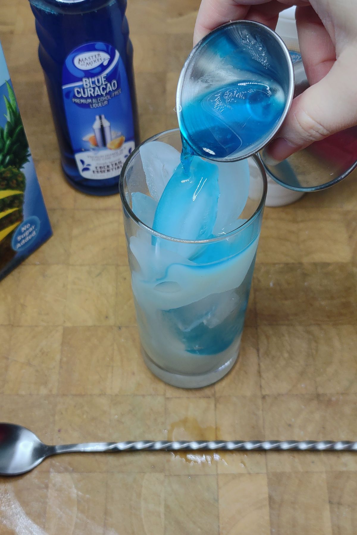 Pouring blue curacao into a glass.
