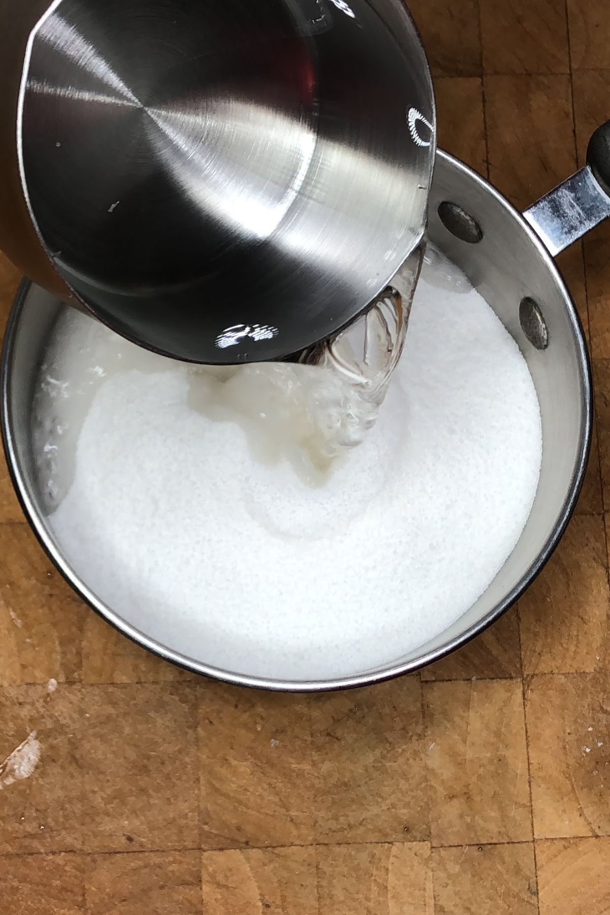 Pouring water into a pot with sugar and coconut.