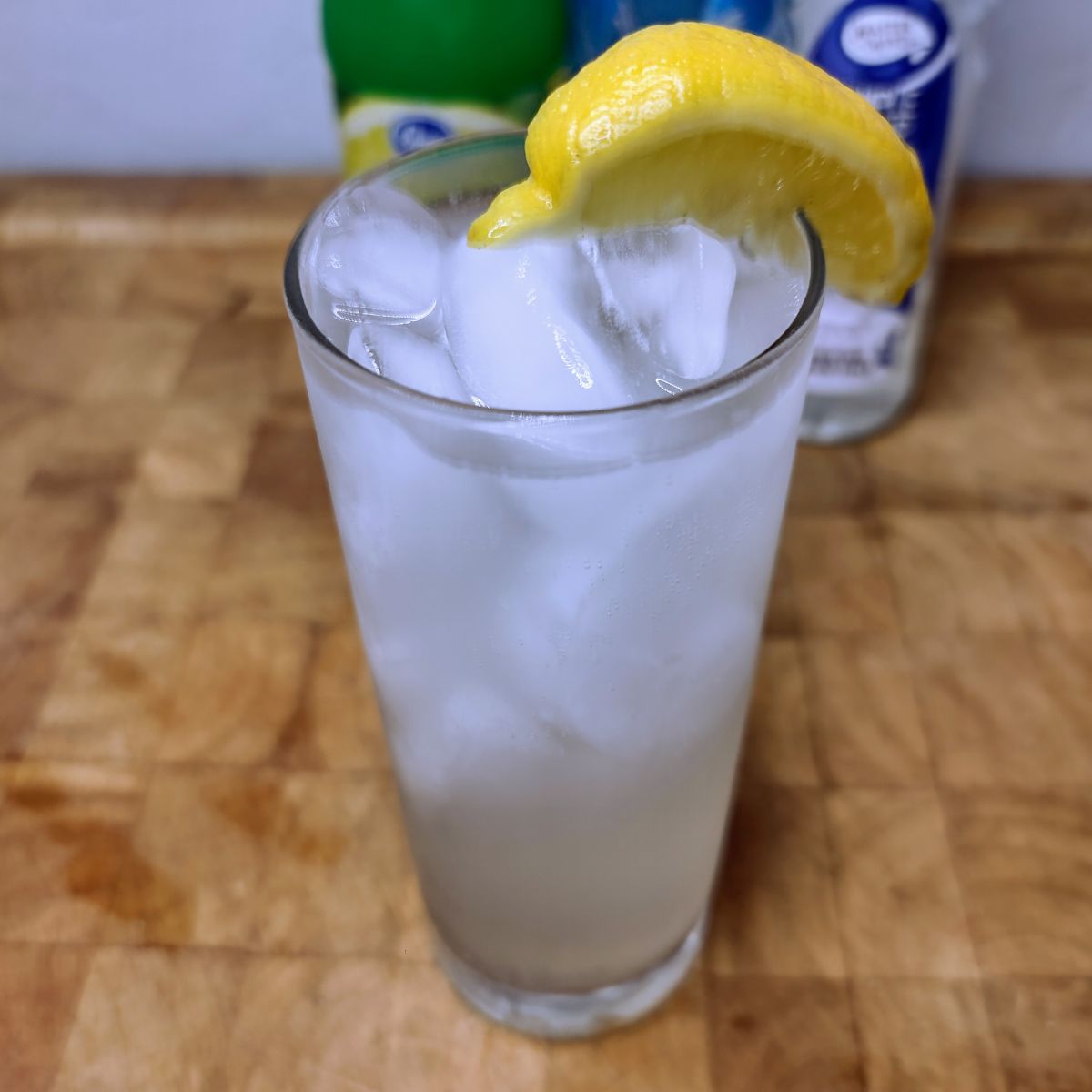 Sparkling Lemonade with a lemon wedge in the glass and ingredients in the background.
