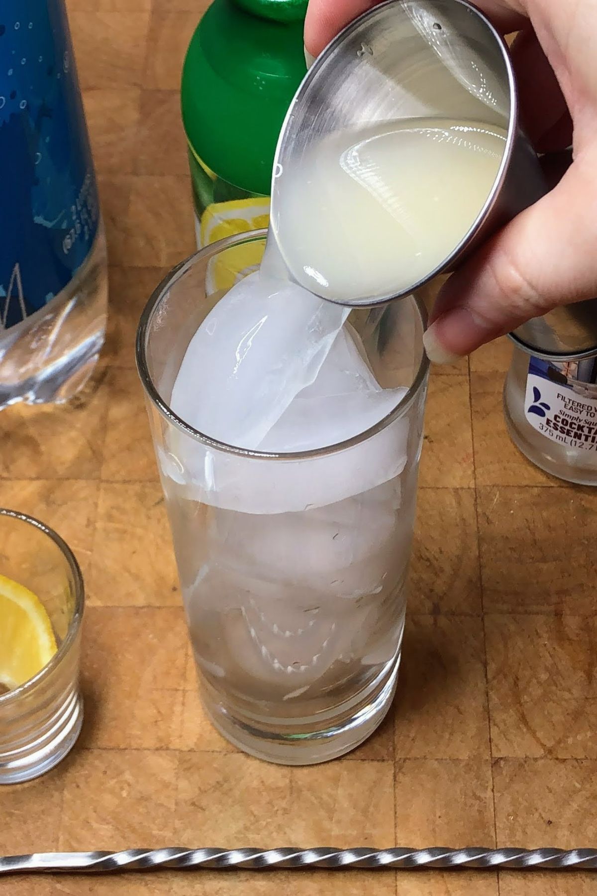 Pouring lemon juice into a highball glass.