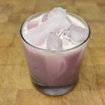 Strawberry Milk in a rocks glass on a wooden table.