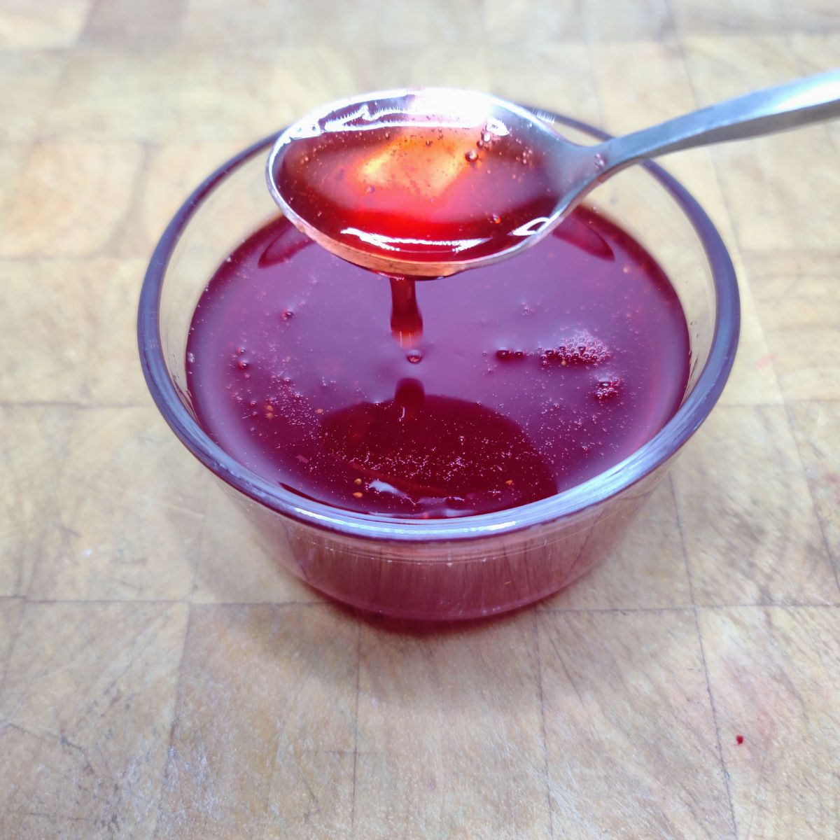 Strawberry Simple Syrup being scooped by a spoon.