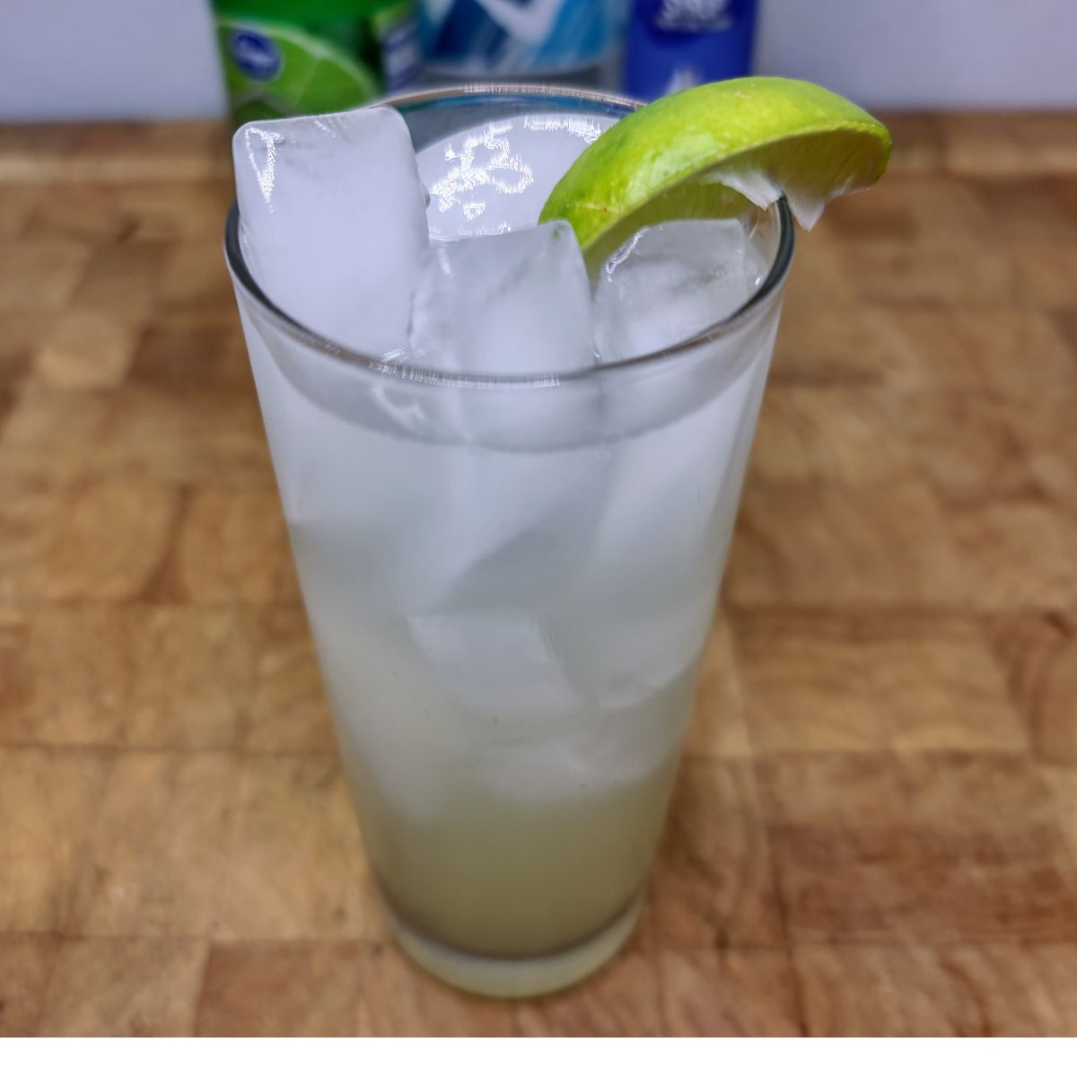 Virgin Lime Rickey with a lime wedge on the glass and ingredients in the background.