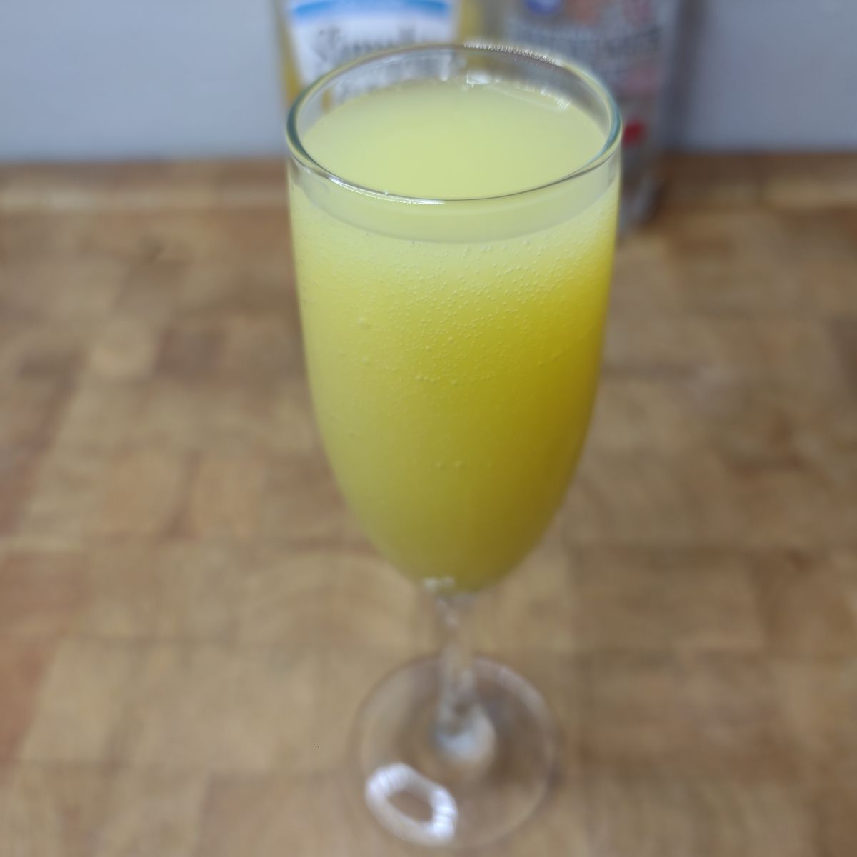 Virgin Mimosa in a champagne flute and ingredients in the background.