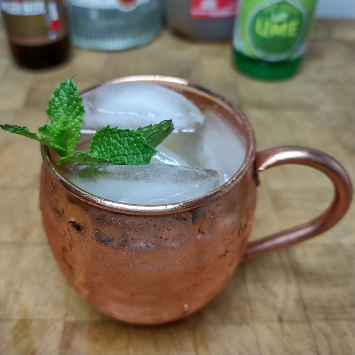 Apple cider mule on a wooden table with ingredients in the background.