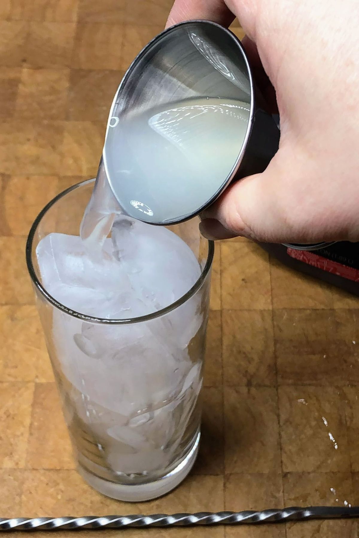 pouring lemonade into a highball glass
