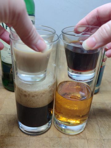 Dropping shot glasses into bear claw drink with ingredients next to the glasses.