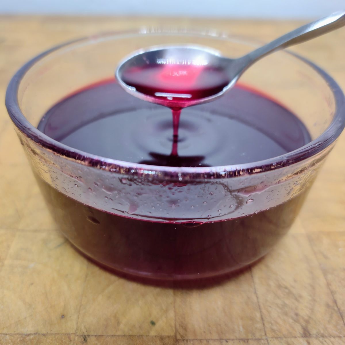 Blackberry simple syrup being scooped by a spoon.