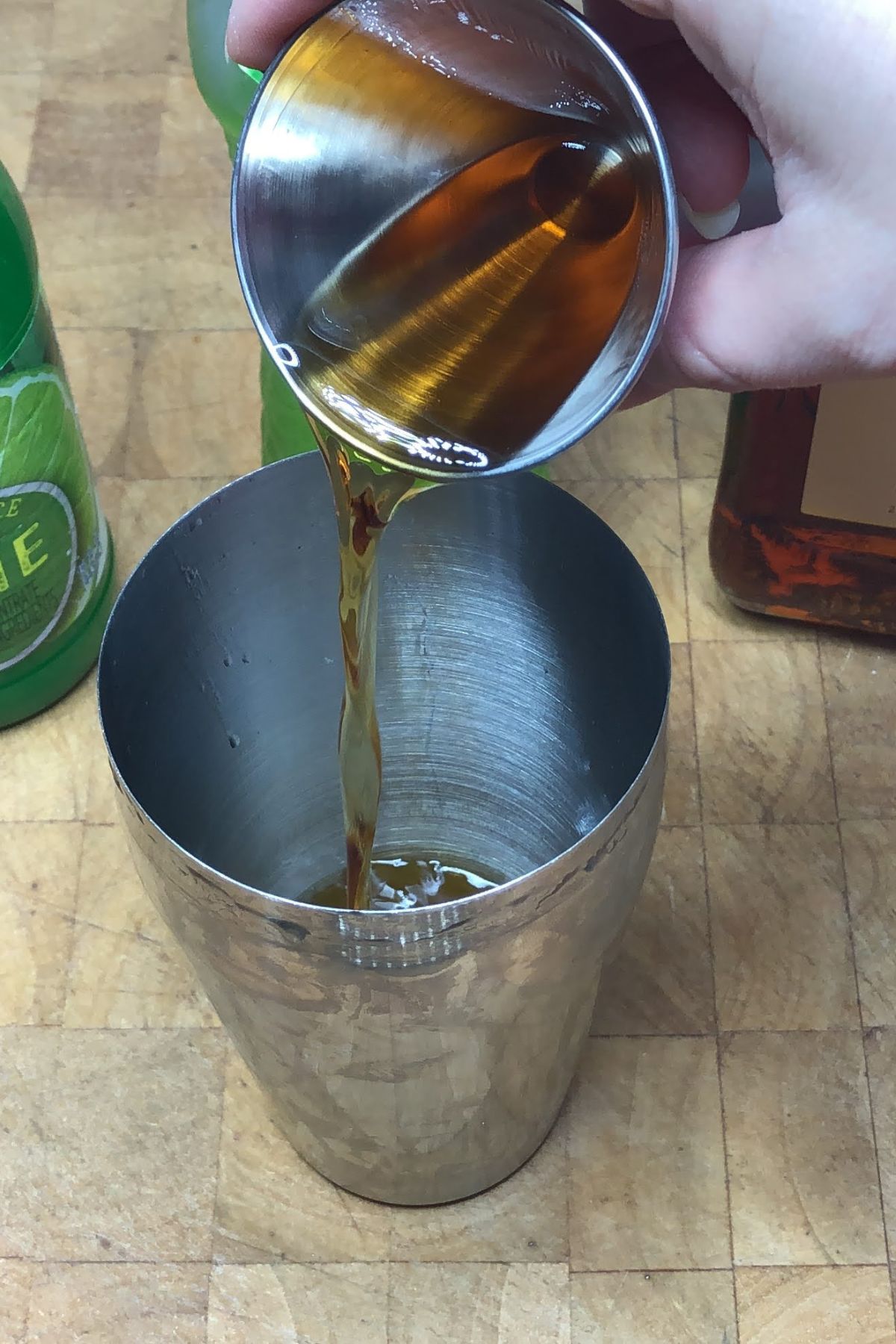 Pouring amaretto from jigger into the shaker.