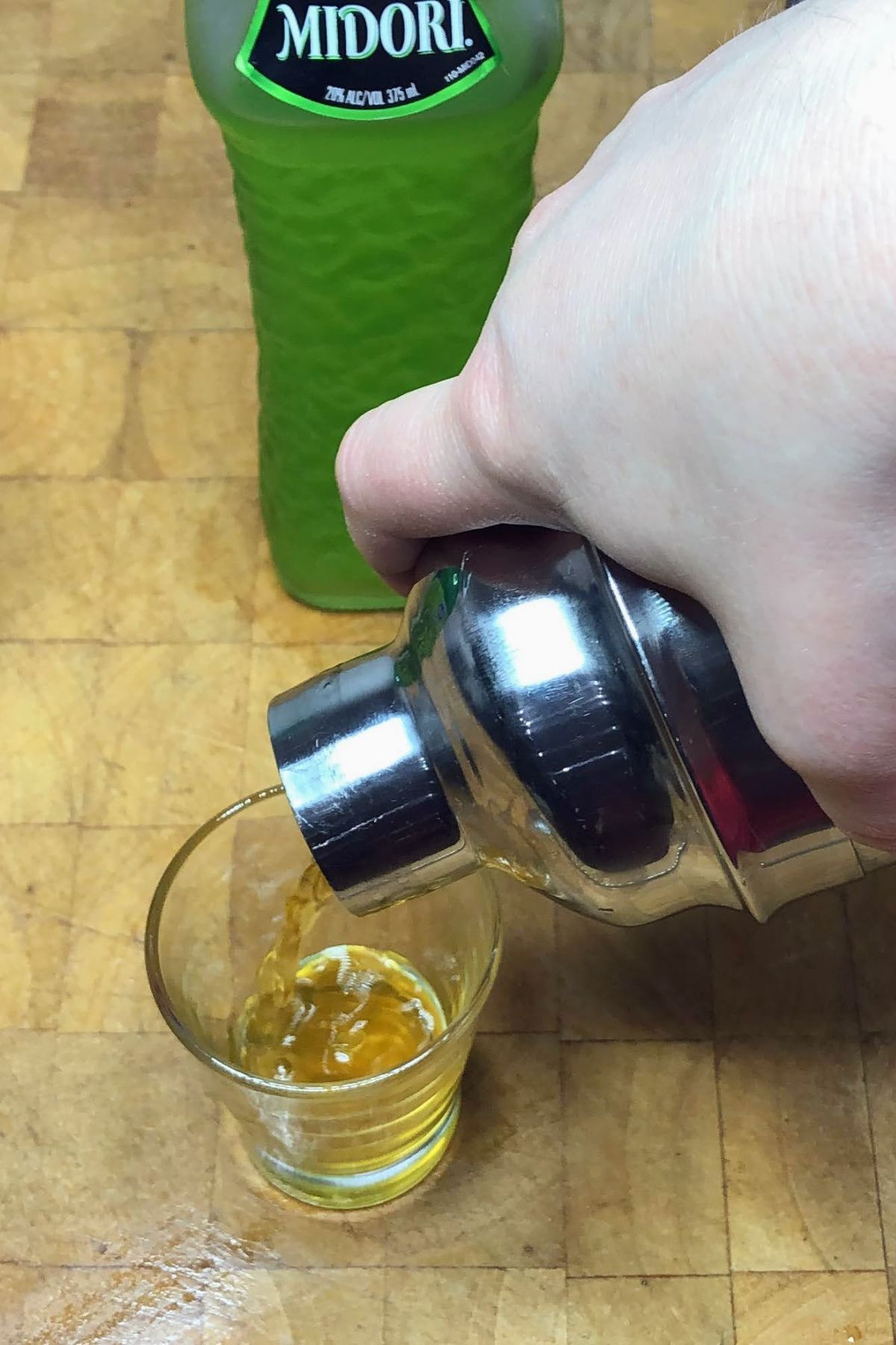 Pouring broken down golf cart shot from shaker into shot glass.