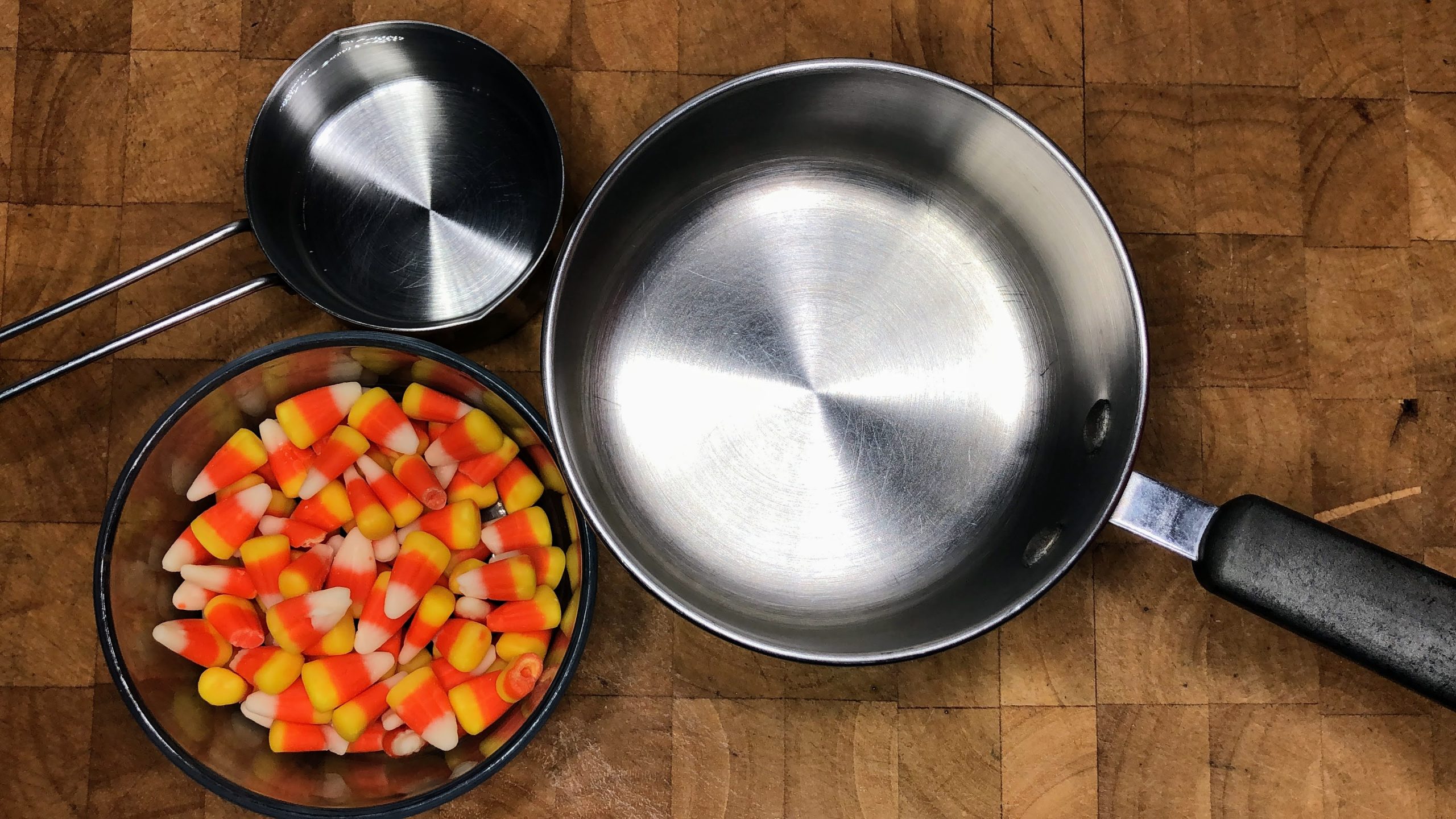 Candy corn and water next to a saucepan.