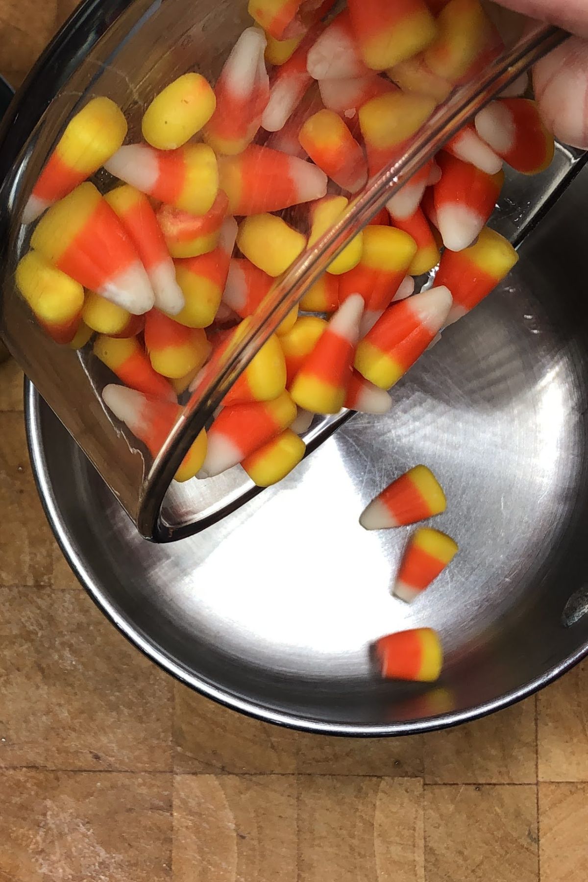 Pouring candy corn into a saucepan.