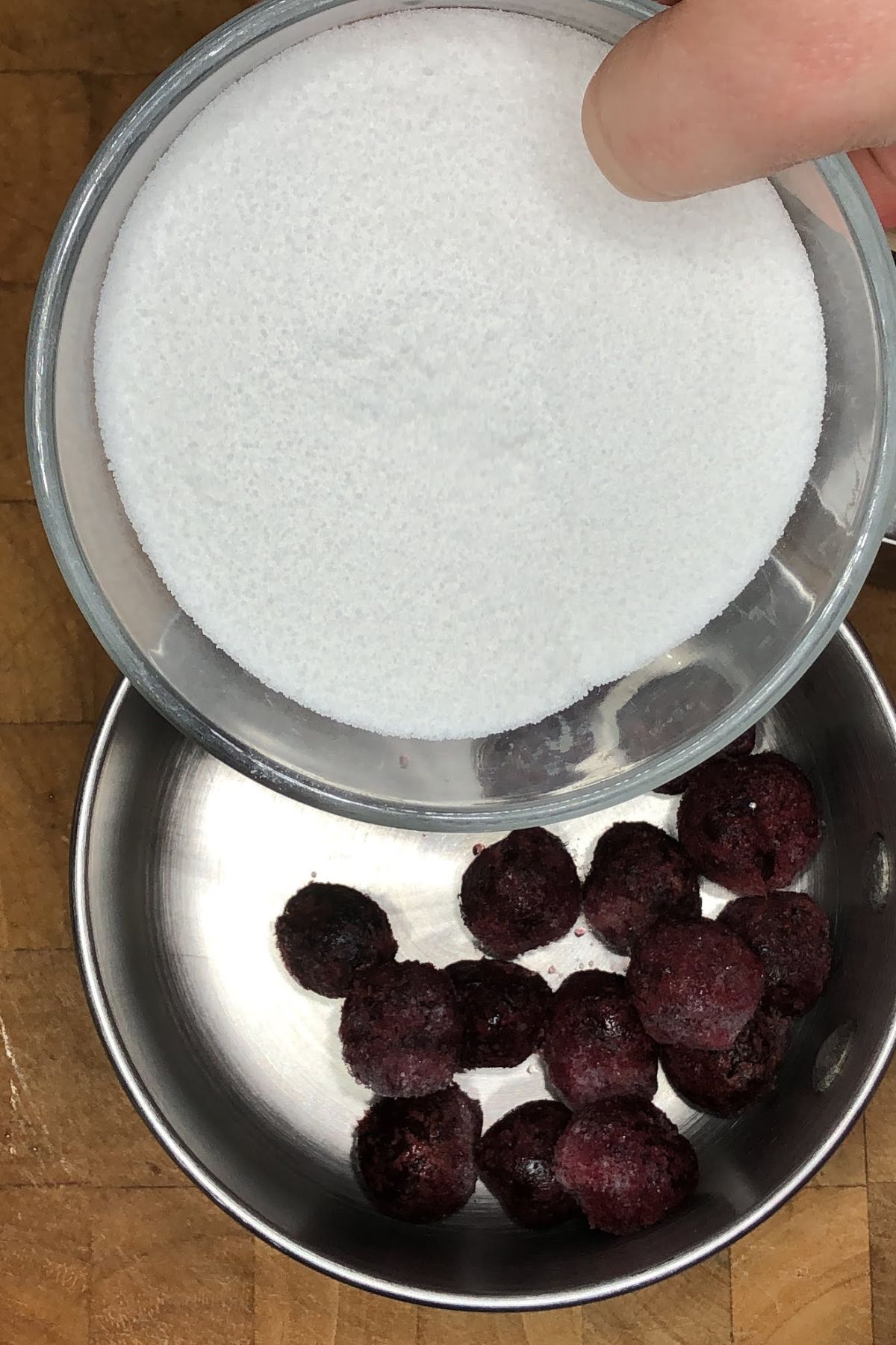 Pouring sugar into a pot with cherries.
