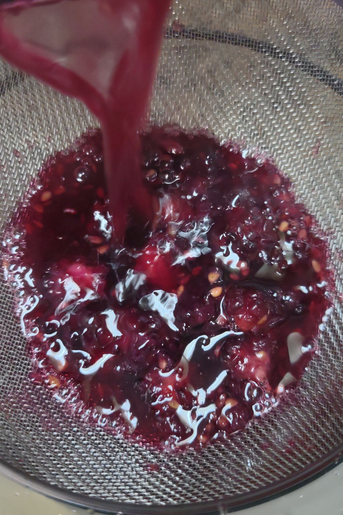 Pouring cherry syrup into a strainer.