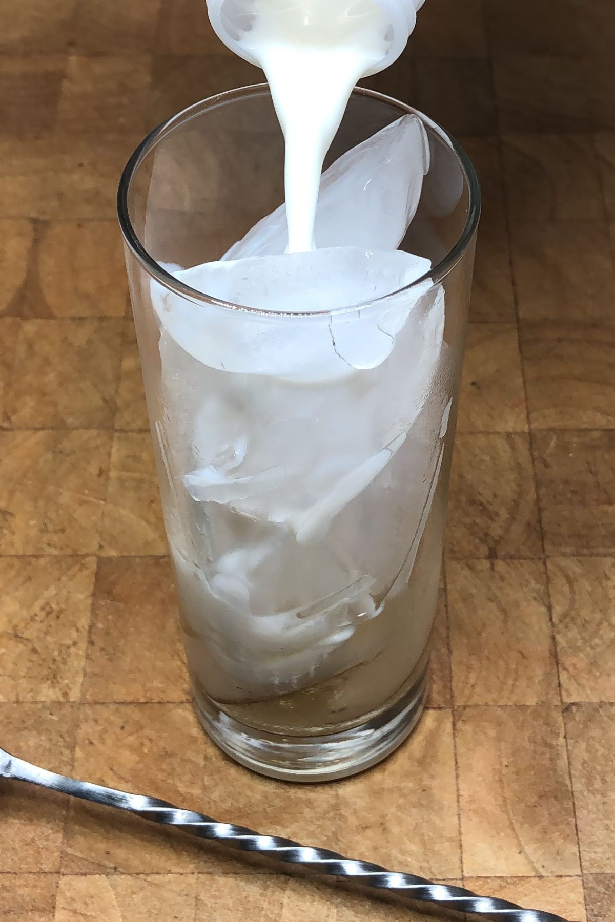 Pouring milk into a highball glass.