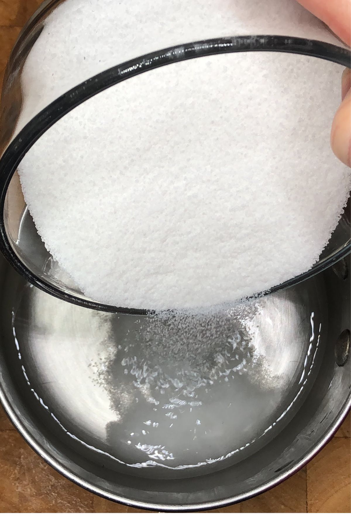 Pouring sugar into a saucepan with water.