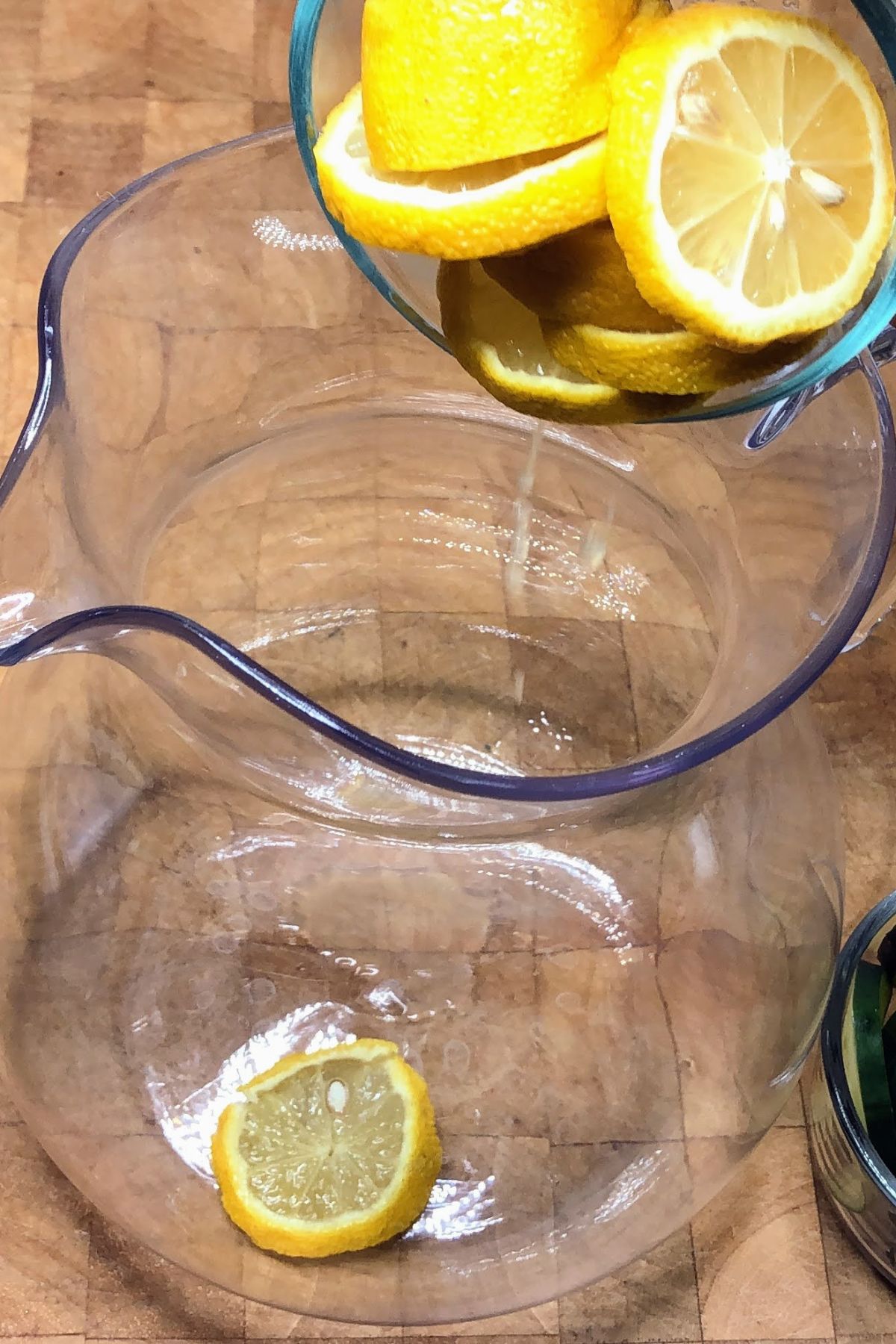 Adding sliced lemons into a pitcher.
