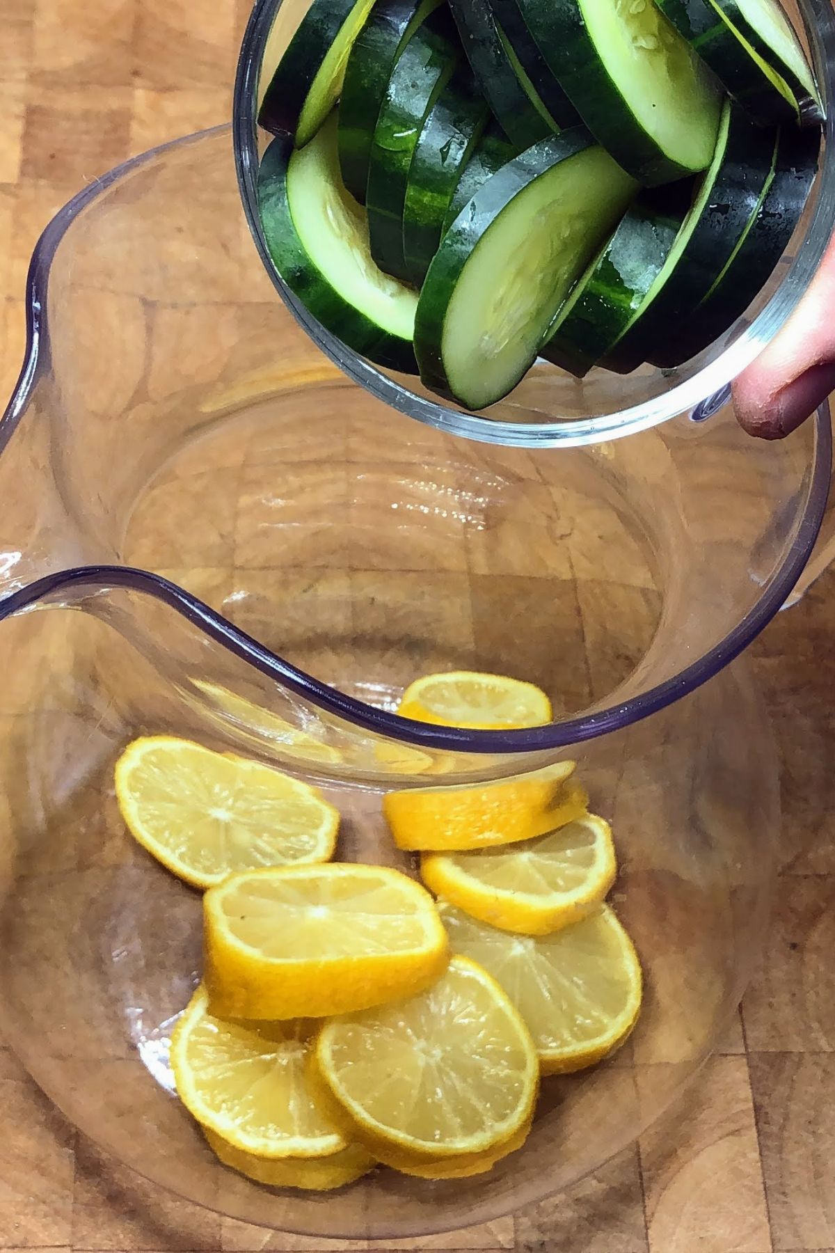 Adding cucumbers into a pitcher.