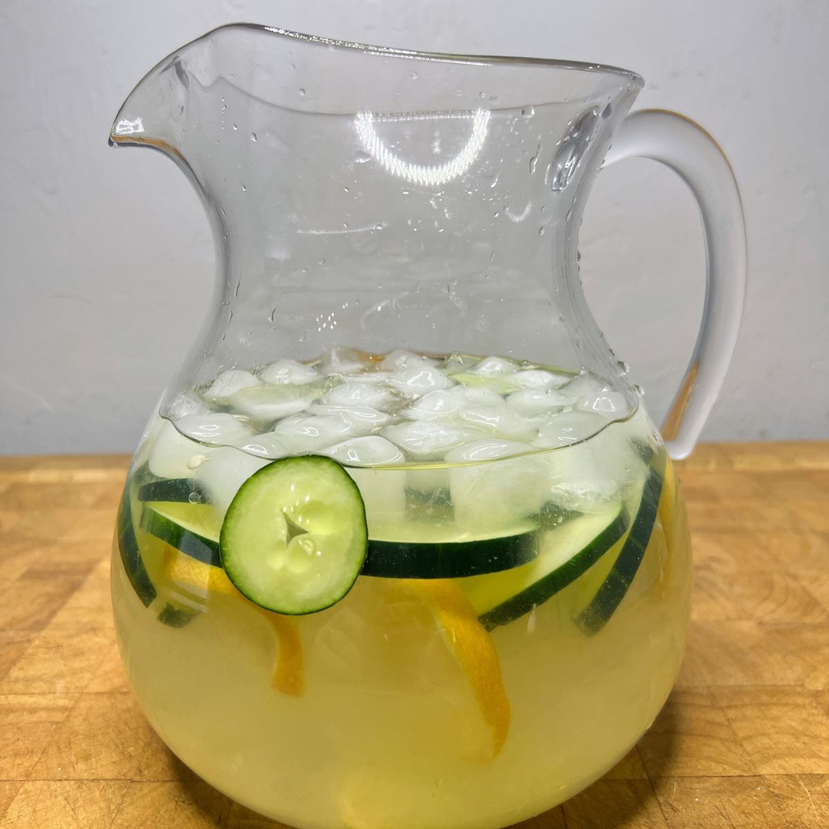 Cucumber lemon water in a pitcher on a wooden table.