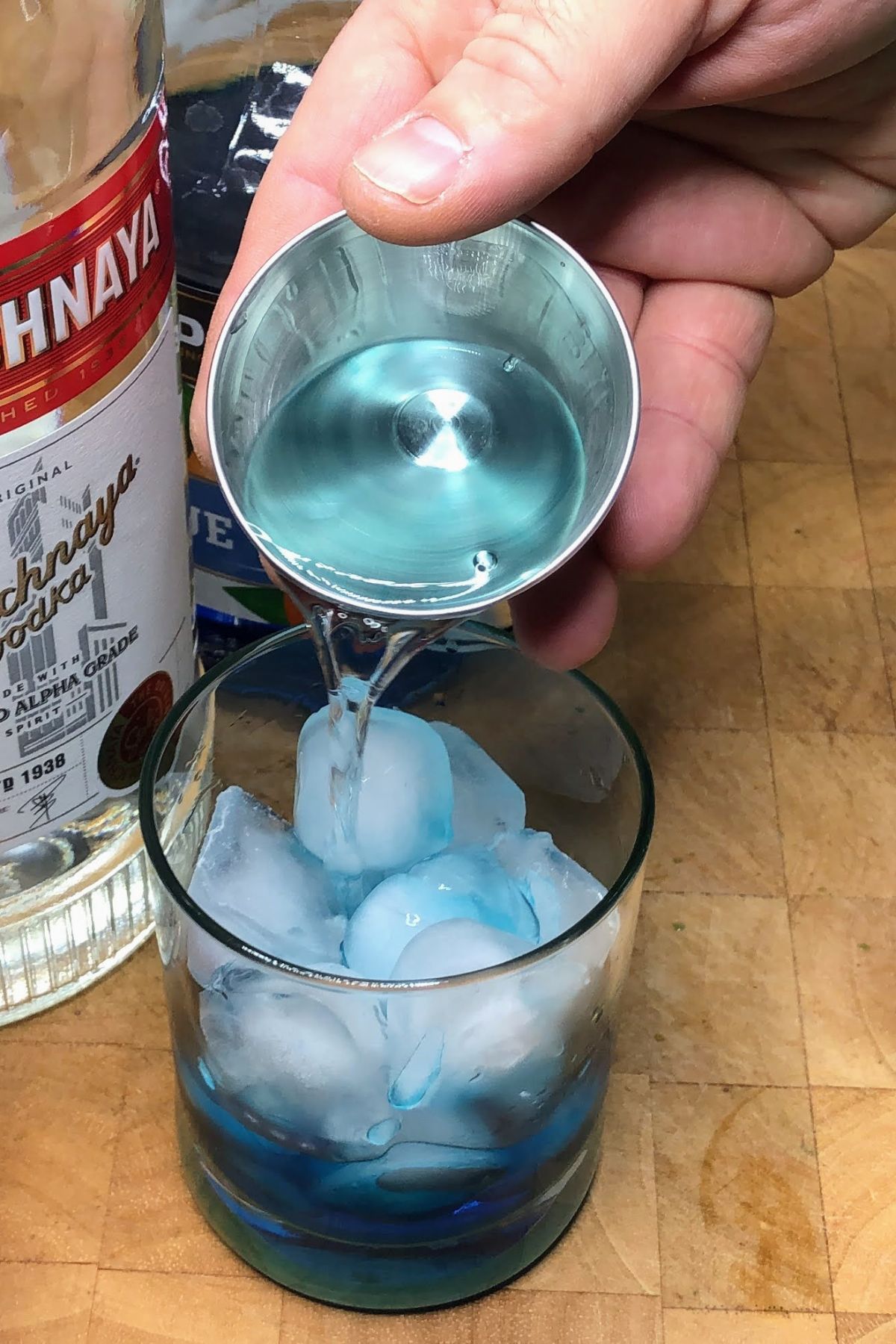 Pouring vodka into a rocks glass.